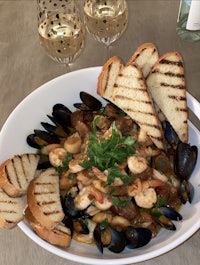 a bowl of seafood stew with bread and wine